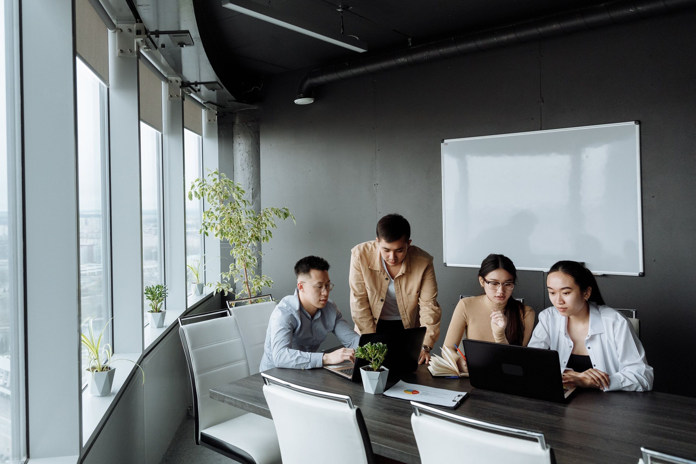 Team working through a plan on laptops in a high-rise meeting room
